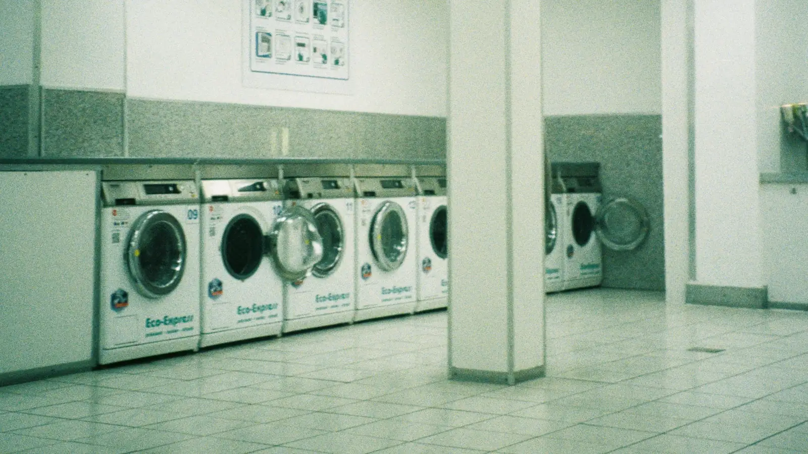 Row of washing machines in a brightly lit self-serve laundromat